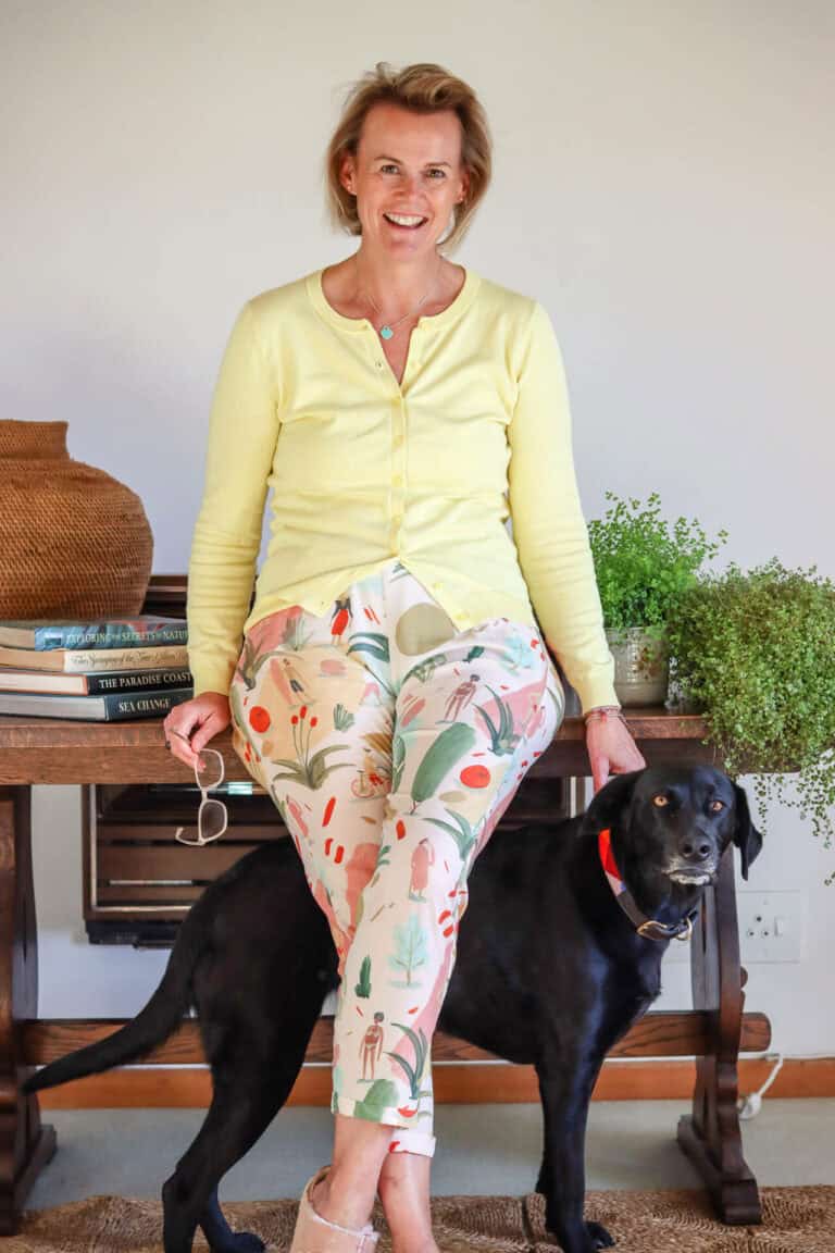 Kerrin Bain leaning against a desk with her black dog below her legs