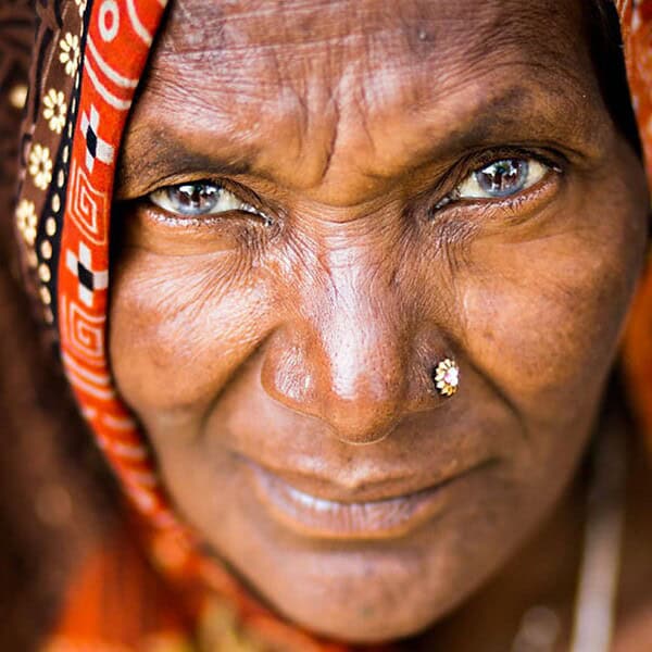 portrait of an indian womans face stares at you framed in a colourful shawl