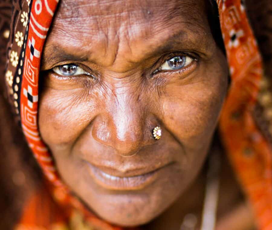 portrait of an indian womans face stares at you framed in a colourful shawl